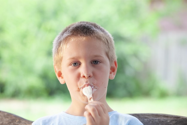 Portrait of cute boy eating ice cream outdoors