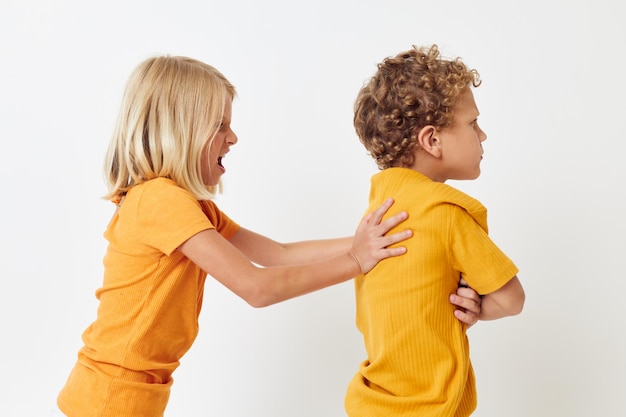 Portrait of cute children in yellow tshirts standing side by side childhood emotions unaltered