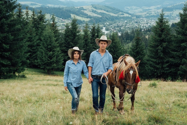 portrait of a cute couple with a horse in a mountains with . Couple walk out horse.