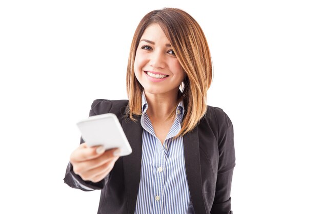 Portrait of a cute female executive for a phone company selling a smartphone and smiling on a white background