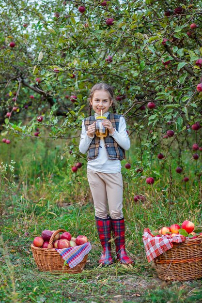 Portrait of a cute girl in a farm garden with a red apple Autumn harvest of apples