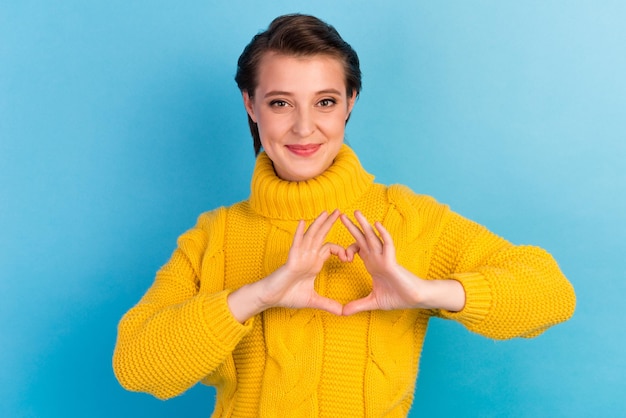 Portrait of cute girl showing heart gesture isolated over bright vivid shine turquoise background