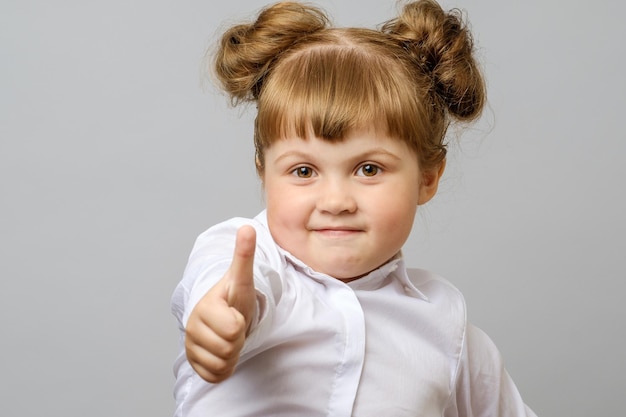 Portrait of cute girl showing thumbs up gesture isolated