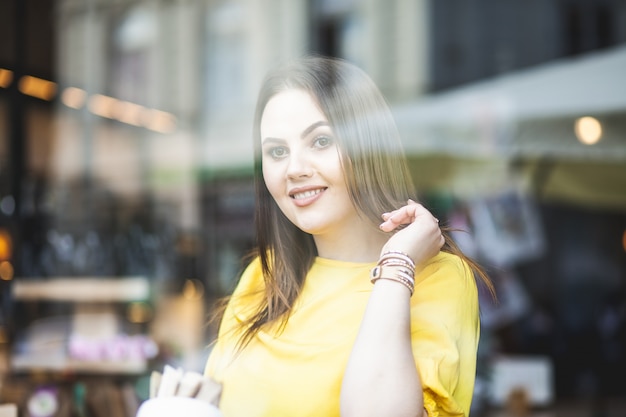 portrait of a cute girl sitting outside the window of a cozy cafe