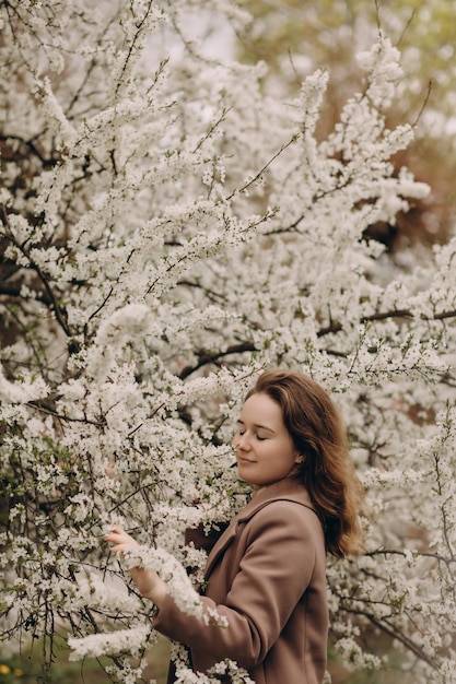 Portrait of a cute girl smiling on a background of flowering spring trees