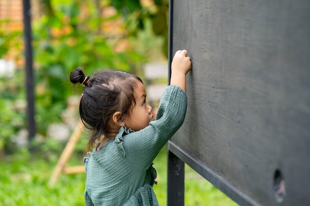 Portrait of cute girl writing alphabet on blackboard