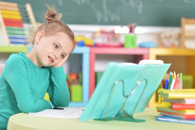 Portrait of cute happy schoolgirl doing homework