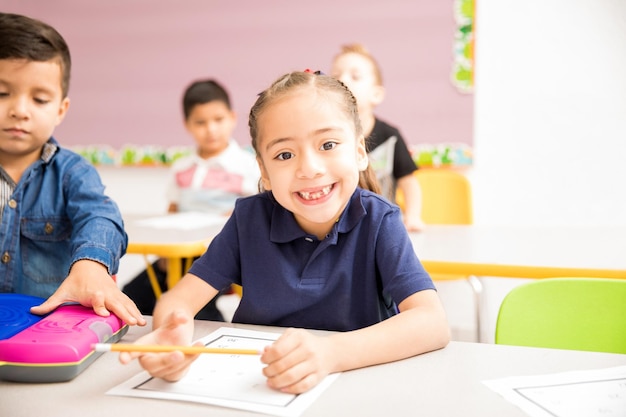 Portrait of a cute Hispanic little girl attending preschool and smiling with a toothless grin