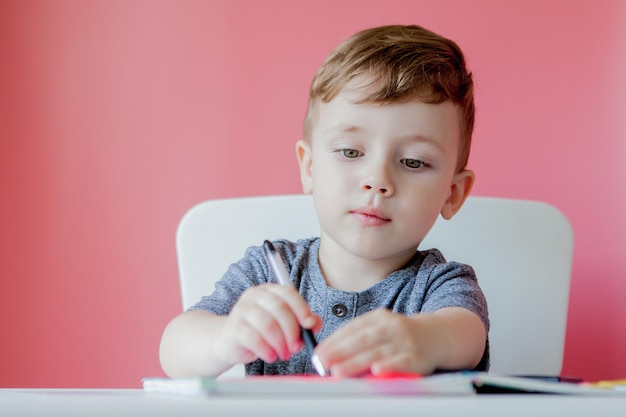 Portrait of cute kid boy at home making homework Little concentrated child writing with colorful pencil indoors Elementary school and education Kid learning writing letters and numbers