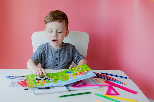 Portrait of cute kid boy at home making homework Little concentrated child writing with colorful pencil indoors Elementary school and education Kid learning writing letters and numbers