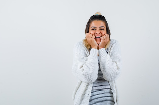 Portrait of cute lady pillowing face on her hands in t-shirt, cardigan and looking merry front view