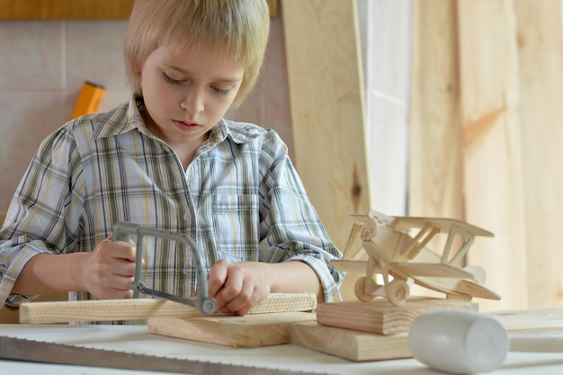 Portrait of cute little boy working with wood in workshop