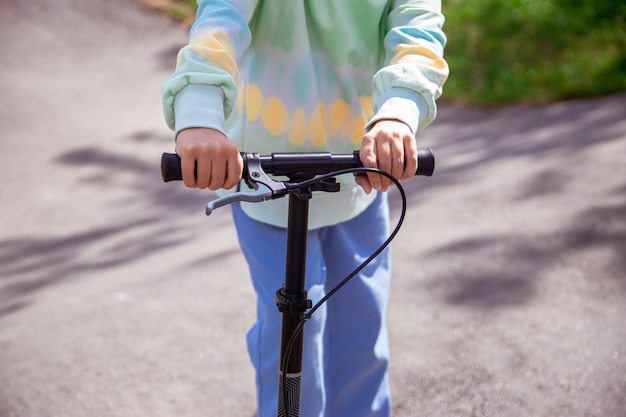 Portrait of cute little caucasian school girl wear helmet enjoy having fun riding scooter on asphalted trackxAin street park outdoors on sunny day Healthy sport children activities outsid