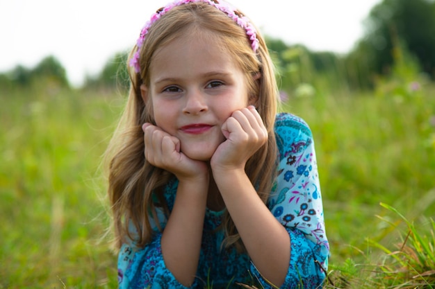 Portrait of a cute little girl lying in a meadow. Beautiful girl 7-9 years old with curly brown hair.