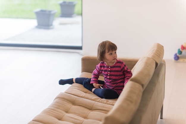 Portrait of cute little girl playing games on smartphone at home