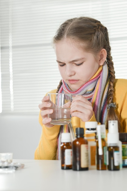 Portrait of a cute little girl taking medicine at home