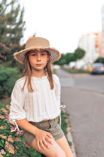 Portrait of a cute little girl with freckles in a straw hat