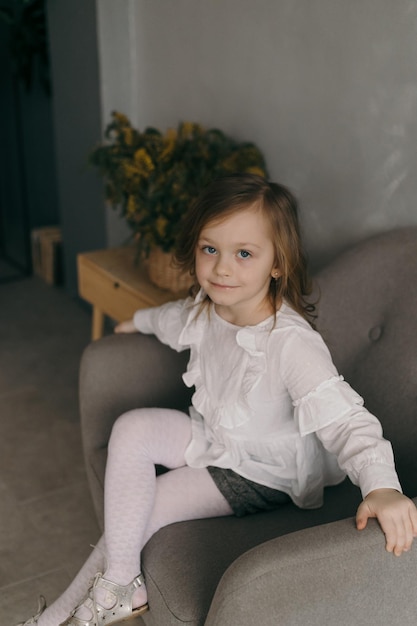 Portrait of cute little girl with long light hair smiling brightfully looking upside on colorful flying balloons with happy and excited expression