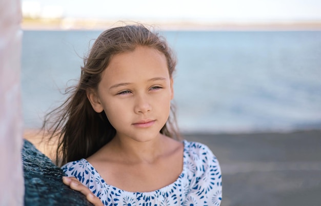 Portrait of cute lonely sad little girl standing thoughtfully at the seaside Dream