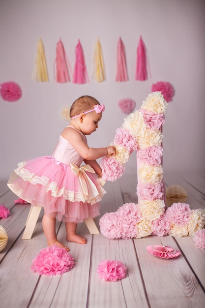 Portrait of cute one yearold baby girl with paper party deko and big number one