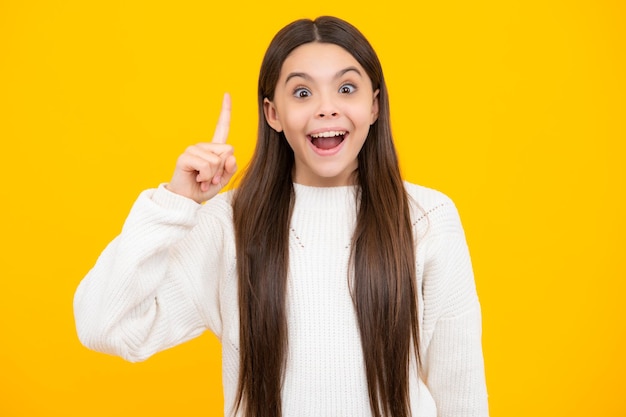 Portrait of cute teenager pointing up with finger Girl has great new idea Successful child Excited