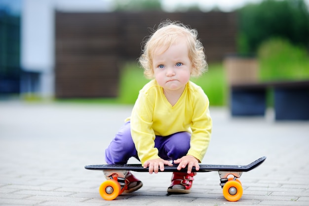 Portrait of cute toddler girl with skateboard outdoors