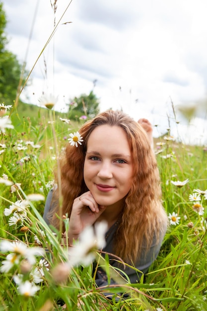 Portrait of cute young girl in dress with wild flowers in summer