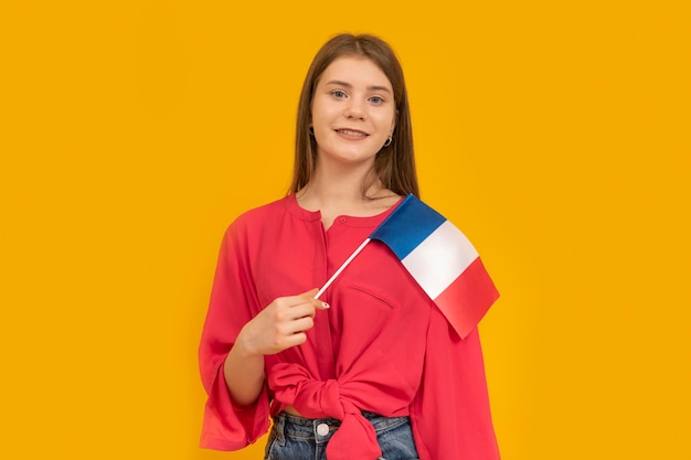 Portrait of cute young girl with the flag of France in her hands on orange background Learn French Immigration to France