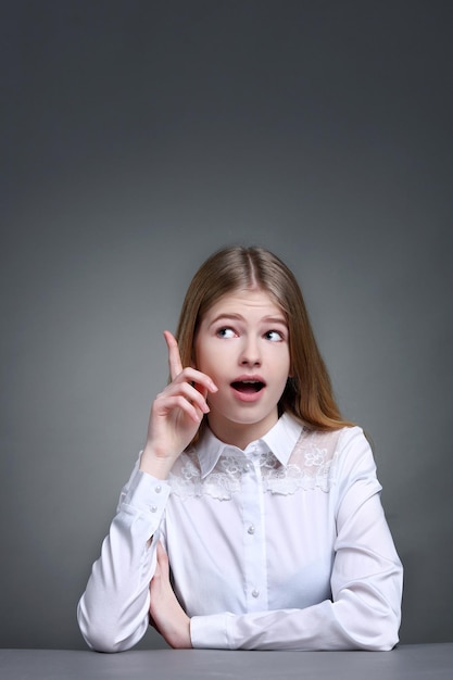 Portrait of a cute young student girl with pondering gesture