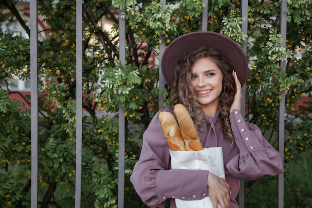 Portrait cute young woman in French style with baguettes in hands