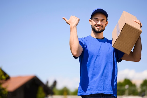 Portrait of delivery man carrying cardboard box