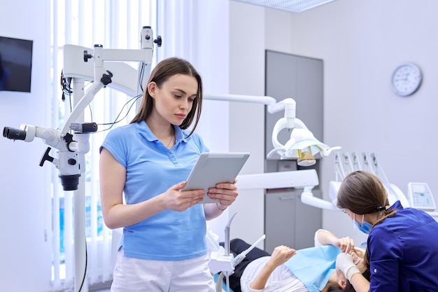 Portrait of dentist doctor with digital tablet, female working with computer. Healthcare dentistry medicine, Dental clinic, patient visit and checkup by dentist background