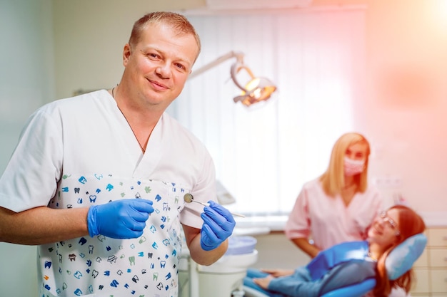 A portrait of a dentist with his team working in the background Stomatology concept