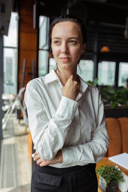 Portrait of determined businesswoman wearing formal white shirt standing in cafe