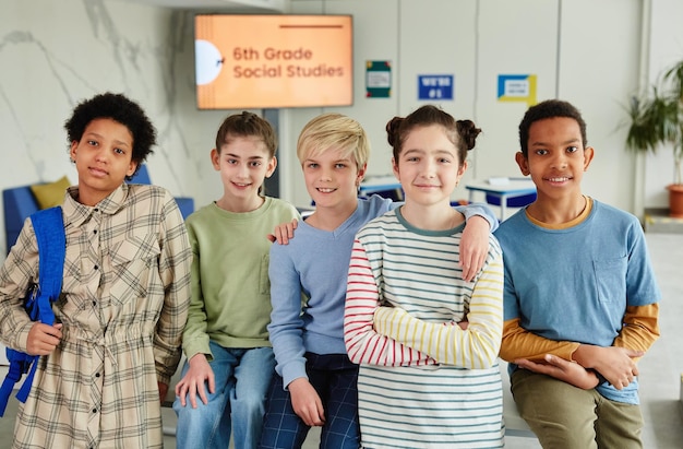 Portrait of diverse group of children looking at camera and smiling while standing together in schoo