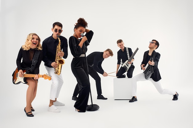 Portrait of diverse group of young people musical band playing with instruments isolated on white background