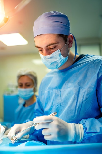 Portrait of a doctor or medical specialist Vertical portrait Man in scrubs Light background with operating room Closeup