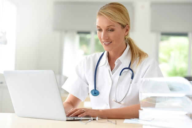 Portrait of doctor in office working on laptop