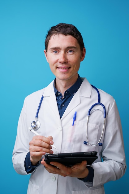 Portrait of doctor with stethoscope and tablet computer in hand on blue background