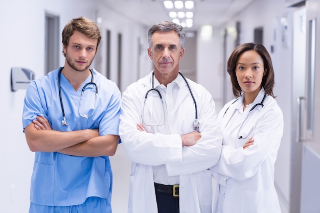 Portrait of doctors standing with arms crossed in corridor