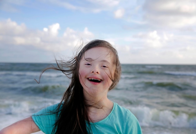 Portrait of down syndrome girl smiling on background of the sea