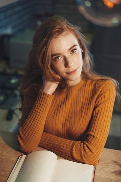 Portrait of a dreamy woman posing looking at camera while reading a book relaxing during work at hom