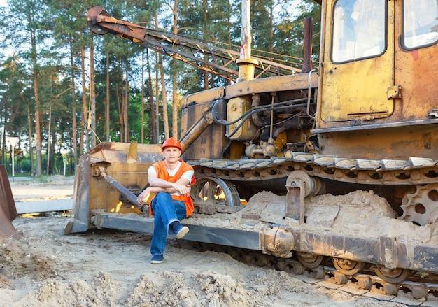 Portrait of driver construction equipment sitting near fuel drums