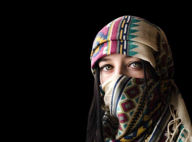 Portrait of eastern young woman in paranja isolated on black background