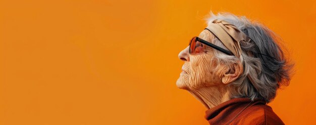 Photo portrait of an elderly caucasian woman with a blindfold against a bright orange background with