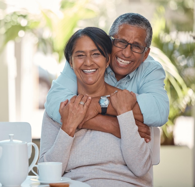 Portrait of elderly couple hug and bonding happy and enjoying tea break at home together Retirement love and smiling man and woman embracing and resting in their house fun and affection affection