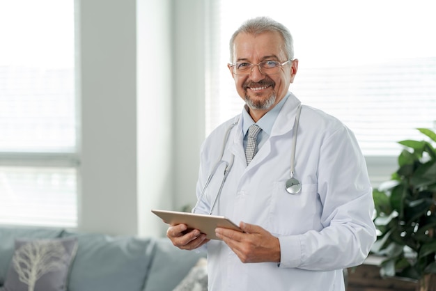 Portrait of an elderly doctor he looks into the camera the doctor stands against the background of a