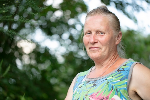 Portrait of an elderly fairhaired woman of normal appearance against a background of greenery