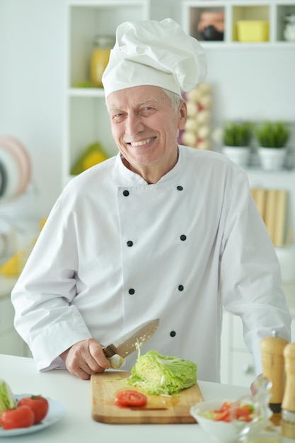 Portrait of elderly male chef cooking at kitchen