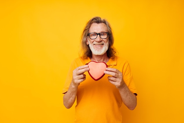 Portrait elderly man yellow tshirt and glasses posing heartshaped box cropped view